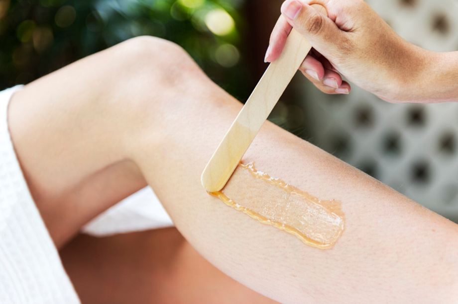 Leg hair being removed with warm wax applied to the shin using a wooden spatula (waxing procedure)